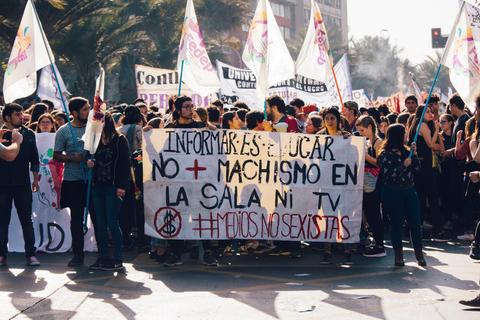 Una multitud participa en una manifestación con pancartas que abogan por la igualdad de género y en contra del machismo.