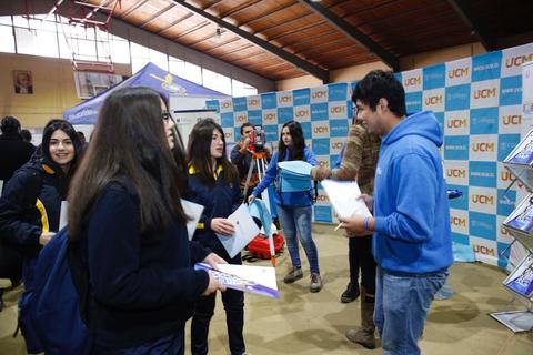 Un grupo de estudiantes interactúa en un evento educativo, recibiendo información y materiales.