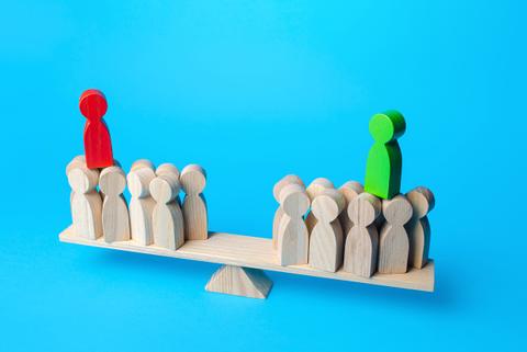 Una balanza de madera con figuras en tonos de color que representan a diferentes grupos de personas.