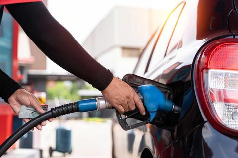 Una persona está llenando el estanque de un auto con combustible en una bomba de bencina.