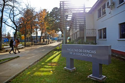 Edificio de la Facultad de Ciencias de la Educación rodeado de naturaleza y estudiantes caminando.
