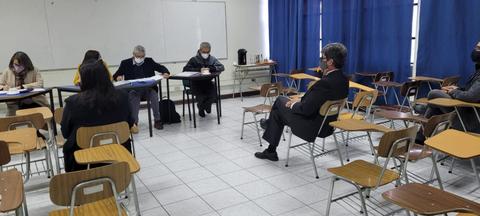 Un grupo de personas sentadas en un aula, algunas tomando notas y otras observando.