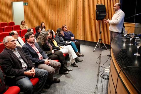 Una persona está dando una presentación frente a un grupo de asistentes en un auditorio.