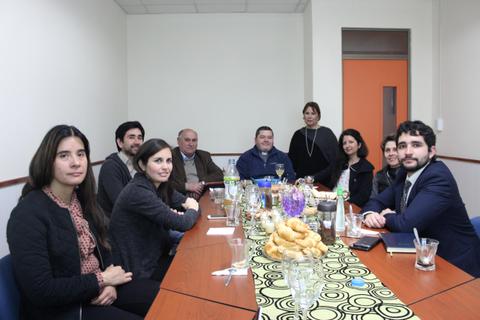 Un grupo de personas se reúne en una sala de reuniones con una mesa decorada y snacks.