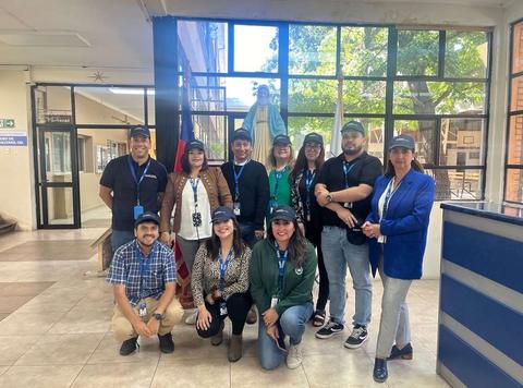 Un grupo de personas sonrientes posando en un interior con una estatua al fondo.
