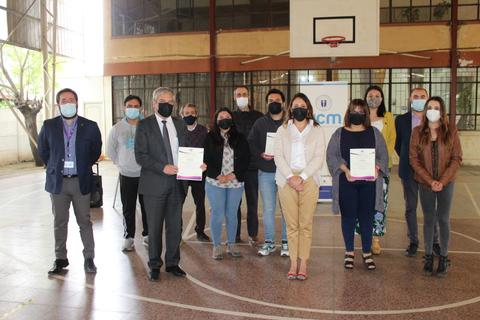 Un grupo de personas se encuentra en un gimnasio sosteniendo certificados y usando mascarillas.