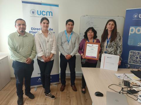 Un grupo de cinco personas posan en una oficina con un certificado en manos.