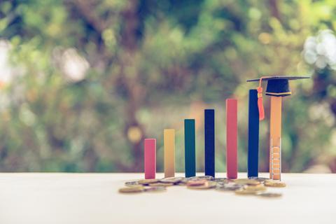 Gráficos de barras con un sombrero de graduación sobre uno de los pilares, simbolizando el crecimiento educativo y financiero.