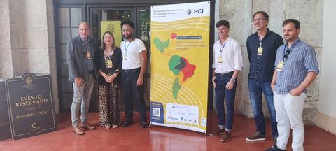 Un grupo de personas posando frente a un cartel en un evento reservado.