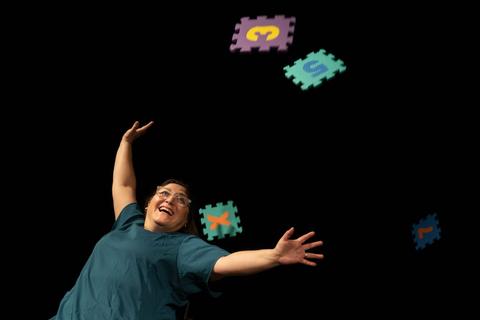 Una persona sonriente lanza piezas de rompecabezas coloridas al aire.