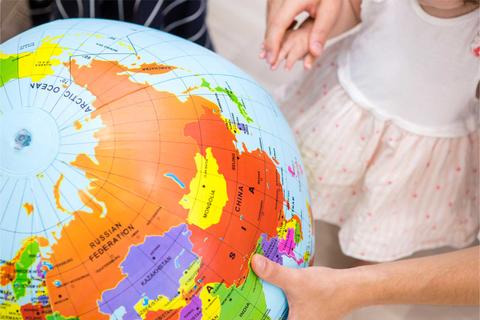 Tres niños están sosteniendo un globo terráqueo mientras exploran los continentes.