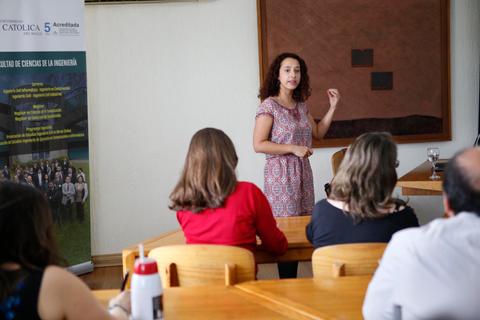 Una mujer está dando una presentación frente a un grupo de personas en una sala de conferencias.