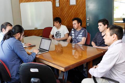 Un grupo de jóvenes discutiendo y trabajando en una mesa durante una reunión.