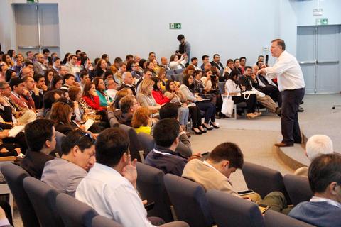 Un orador presenta ante un público numeroso en un evento o conferencia.
