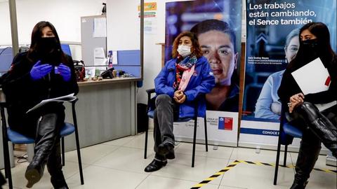 Tres personas se encuentran sentadas en una oficina, dialogando y con medidas de protección sanitaria.