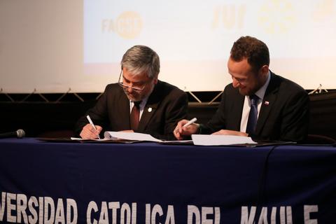Dos hombres firmando un acuerdo en un evento oficial de la Universidad Católica del Maule.