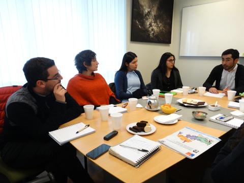 Un grupo de personas discutiendo en una mesa con varias tazas y documentos frente a ellos.