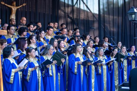 Un coro vestido con túnicas azules y doradas canta en un escenario.