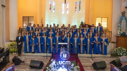 Un grupo de personas vestidas con túnicas azules se encuentra en un escenario dentro de una iglesia.
