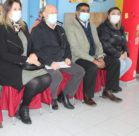 Un grupo de cuatro personas sentadas en una sala con mascarillas.