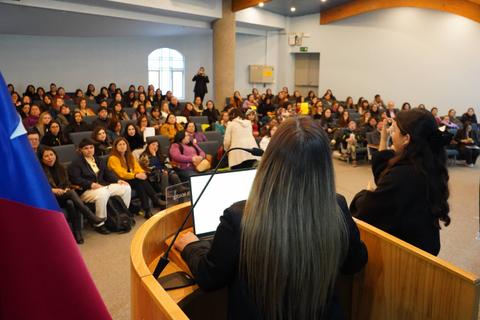 Un evento con muchas personas escuchando desde el público en una sala amplia.