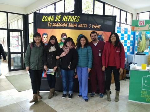 Un grupo de seis personas sonríen frente a una pancarta que promueve la donación de sangre.