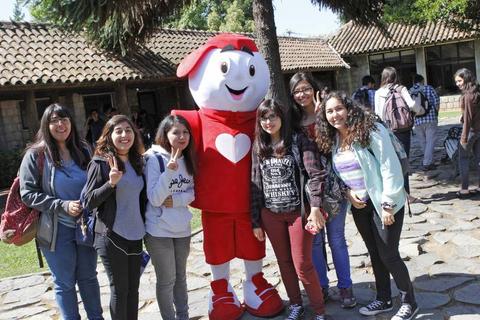 Un grupo de jóvenes sonríe junto a un personaje disfrazado en un evento al aire libre.