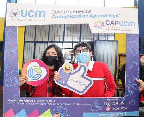 Estudiantes posando con marcos y letreros en un evento de la Universidad Católica del Maule.