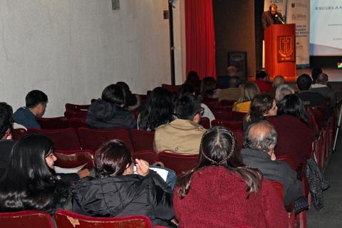 Una audiencia atenta escucha a un presentador en un evento.