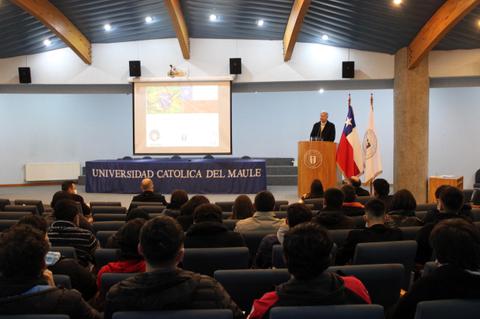 Un ponente hablando frente a una audiencia en un auditorio de la Universidad Católica del Maule.
