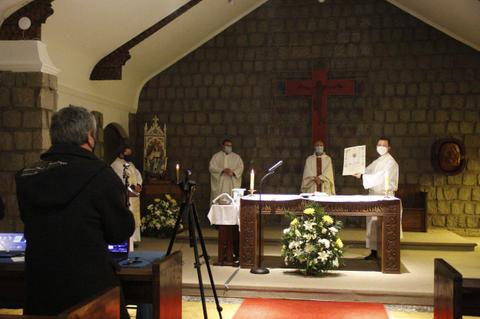 Una ceremonia religiosa en una iglesia con varios sacerdotes y un fotógrafo al fondo.