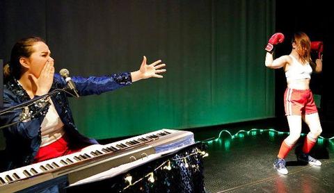 Una cantante acompaña a una boxeadora en una actuación en el escenario.