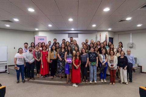 Un grupo de personas posando en un evento académico en un auditorio.