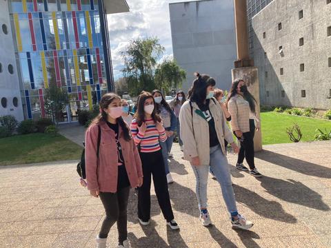 Un grupo de jóvenes camina por un espacio al aire libre cerca de un edificio moderno.