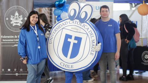 Un grupo de estudiantes posando junto a una mascota de la Universidad Católica del Maule en un evento.