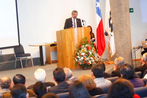 Un orador habla desde un podio en un evento público mientras la audiencia escucha atentamente.
