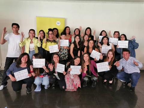 Un grupo de personas sonrientes posando con documentos en una sala.