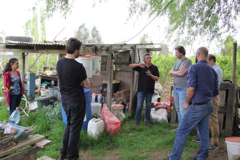 Un grupo de personas se reúne en un espacio al aire libre mientras uno de ellos explica algo.