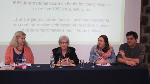 Una mesa redonda con cuatro personas discutiendo sobre la organización IBBY, que promueve la literatura infantil a nivel internacional.