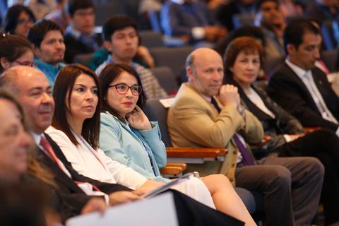 Un grupo de personas sentadas en una conferencia, prestando atención al orador.