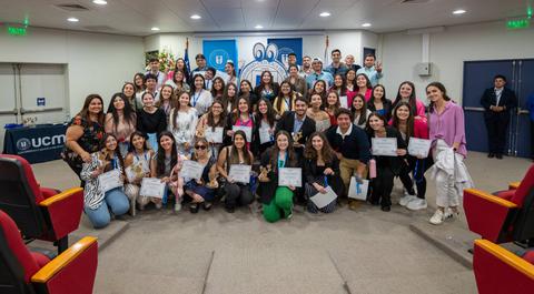 Un grupo de personas sonrientes sosteniendo certificados en un evento de entrega de diplomas.