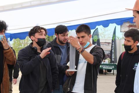 Un grupo de jóvenes se reúne para observar un objeto en una mano mientras discuten entre ellos.