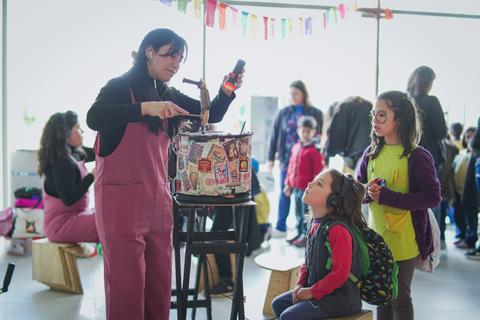 Una mujer está realizando una actividad creativa mientras los niños la observan con atención.
