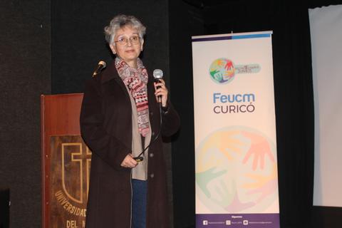 Mujer hablando con un micrófono en un evento en la universidad.