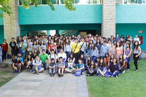 Un grupo grande de estudiantes posando juntos en un ambiente exterior escolar.