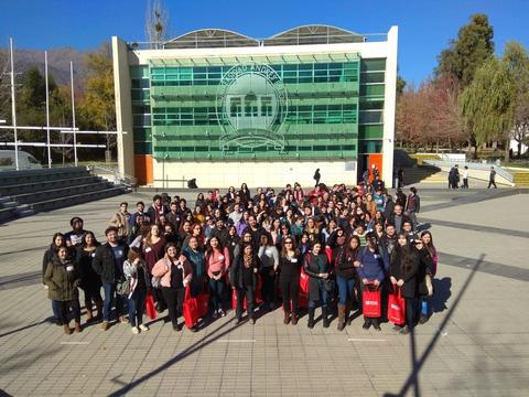Un grupo numeroso de personas posando en un lugar al aire libre frente a un edificio moderno.