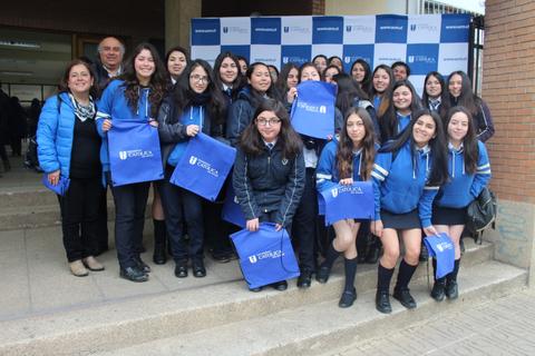 Un grupo de estudiantes posando juntos con mochilas en una ceremonia escolar.