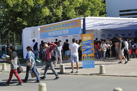 Un grupo de estudiantes se registra en un stand de matrículas universitarias al aire libre.