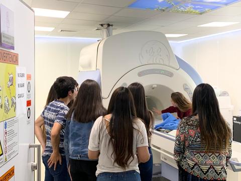 Un grupo de personas observa una máquina de resonancia magnética en un entorno clínico.