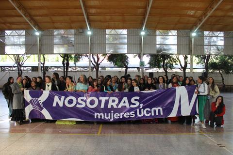 Un grupo de mujeres se reúne sosteniendo una pancarta en un evento de la UCM.